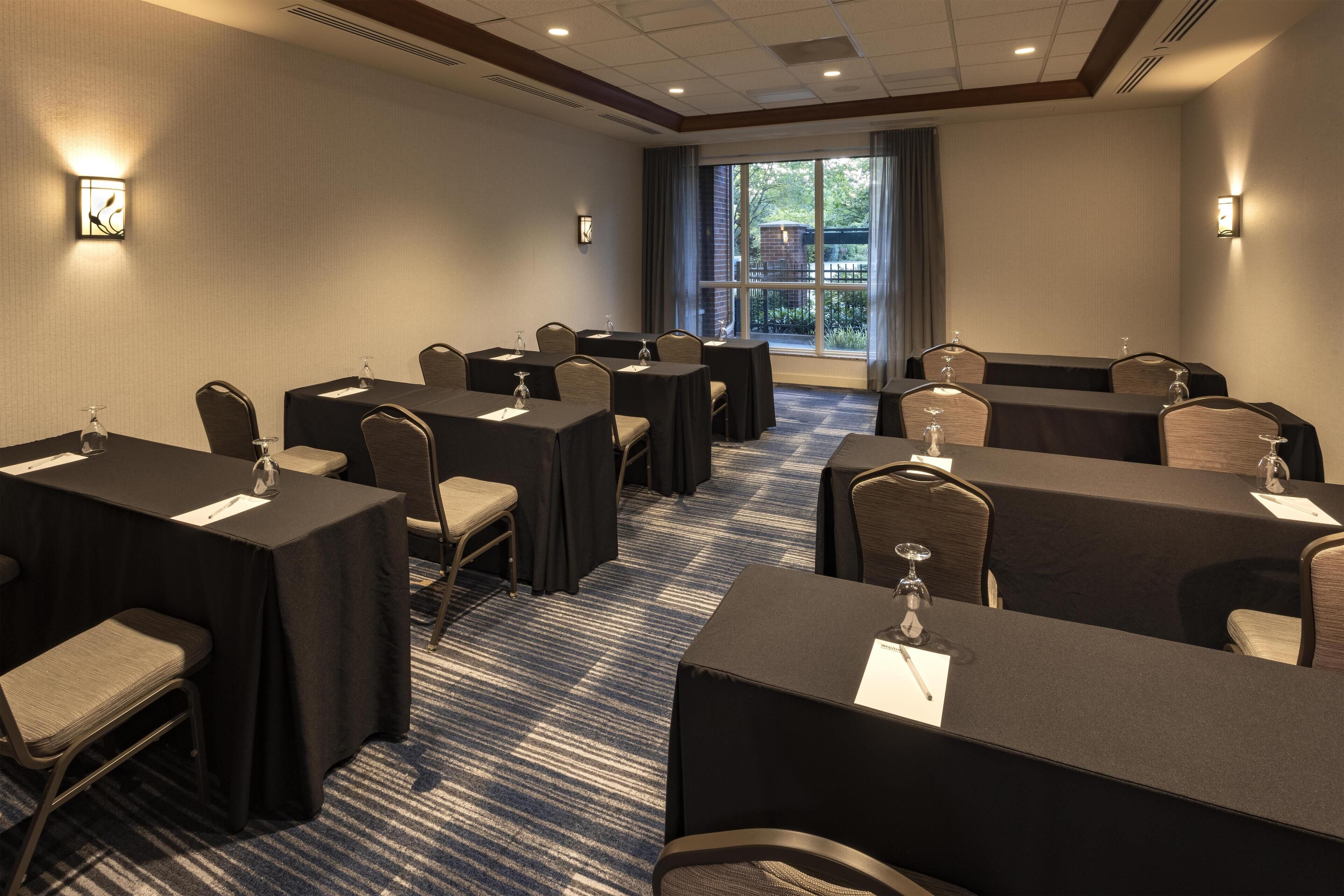 A conference room with tables, chairs, and a large window.