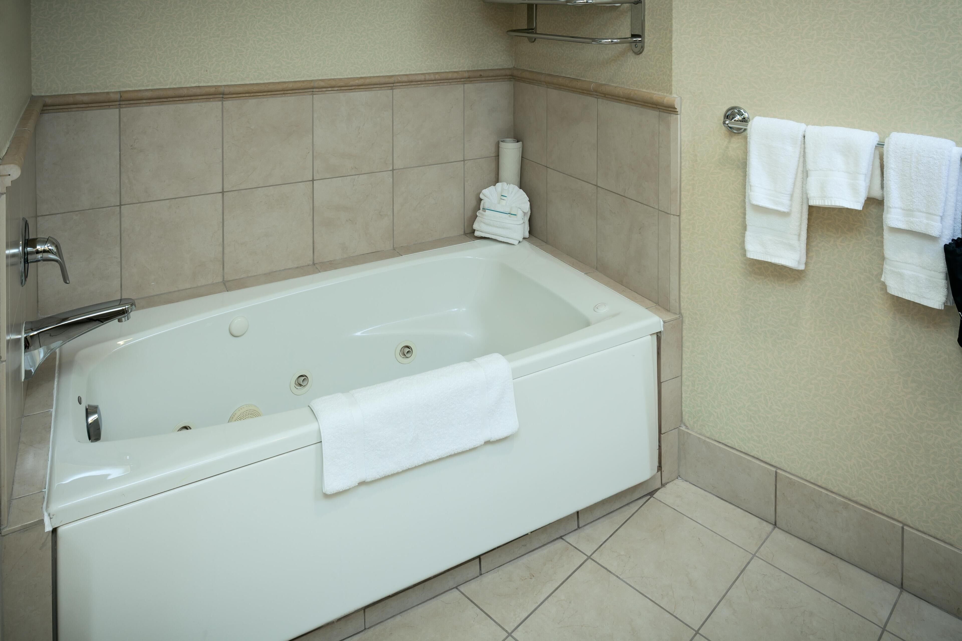 A bathroom with a white bathtub, a towel rack with towels, and a toilet paper holder.