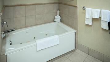 A bathroom with a white bathtub, a towel rack with towels, and a toilet paper holder.