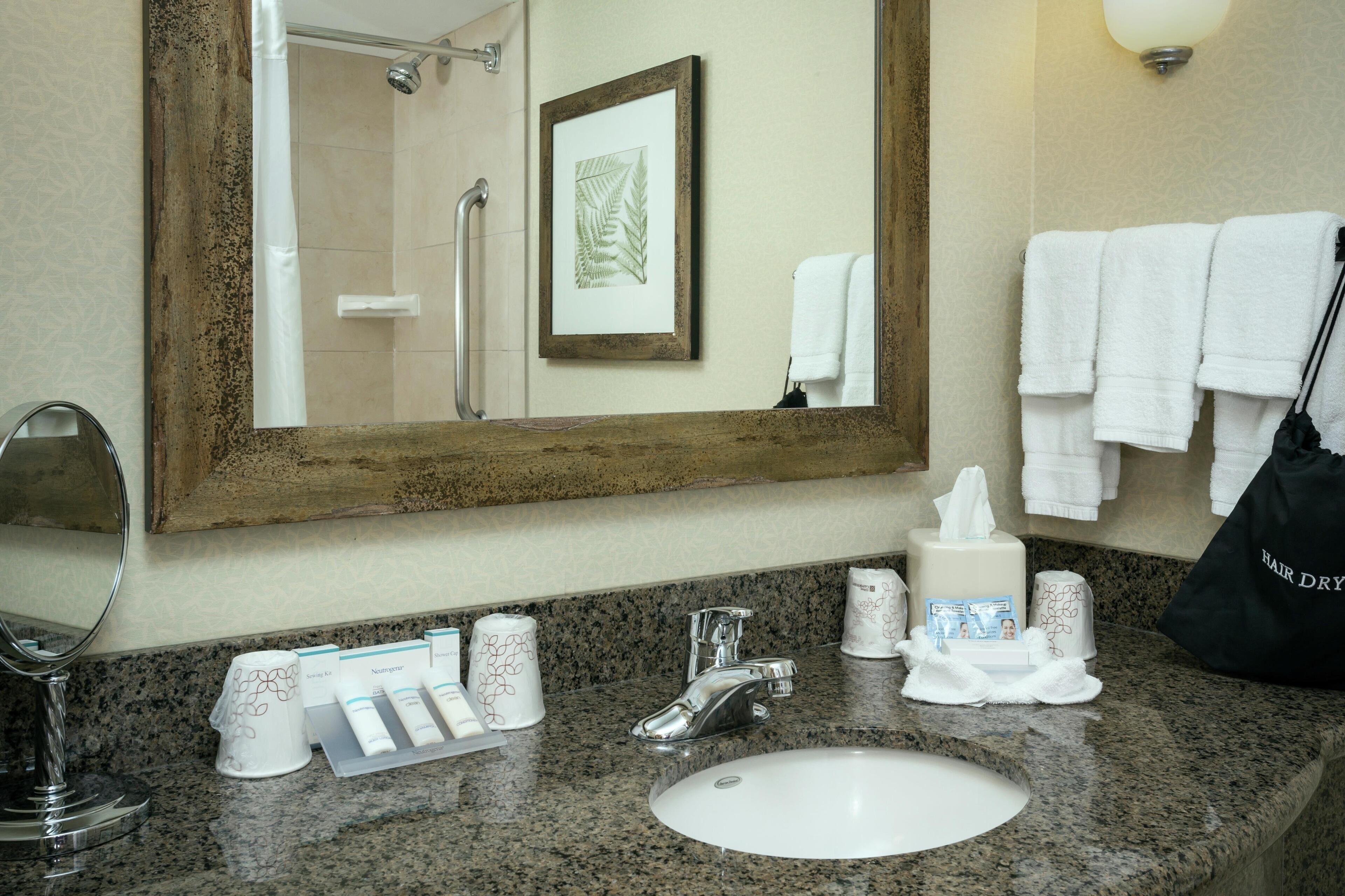 A bathroom with a sink, mirror, towel rack, and toiletries.