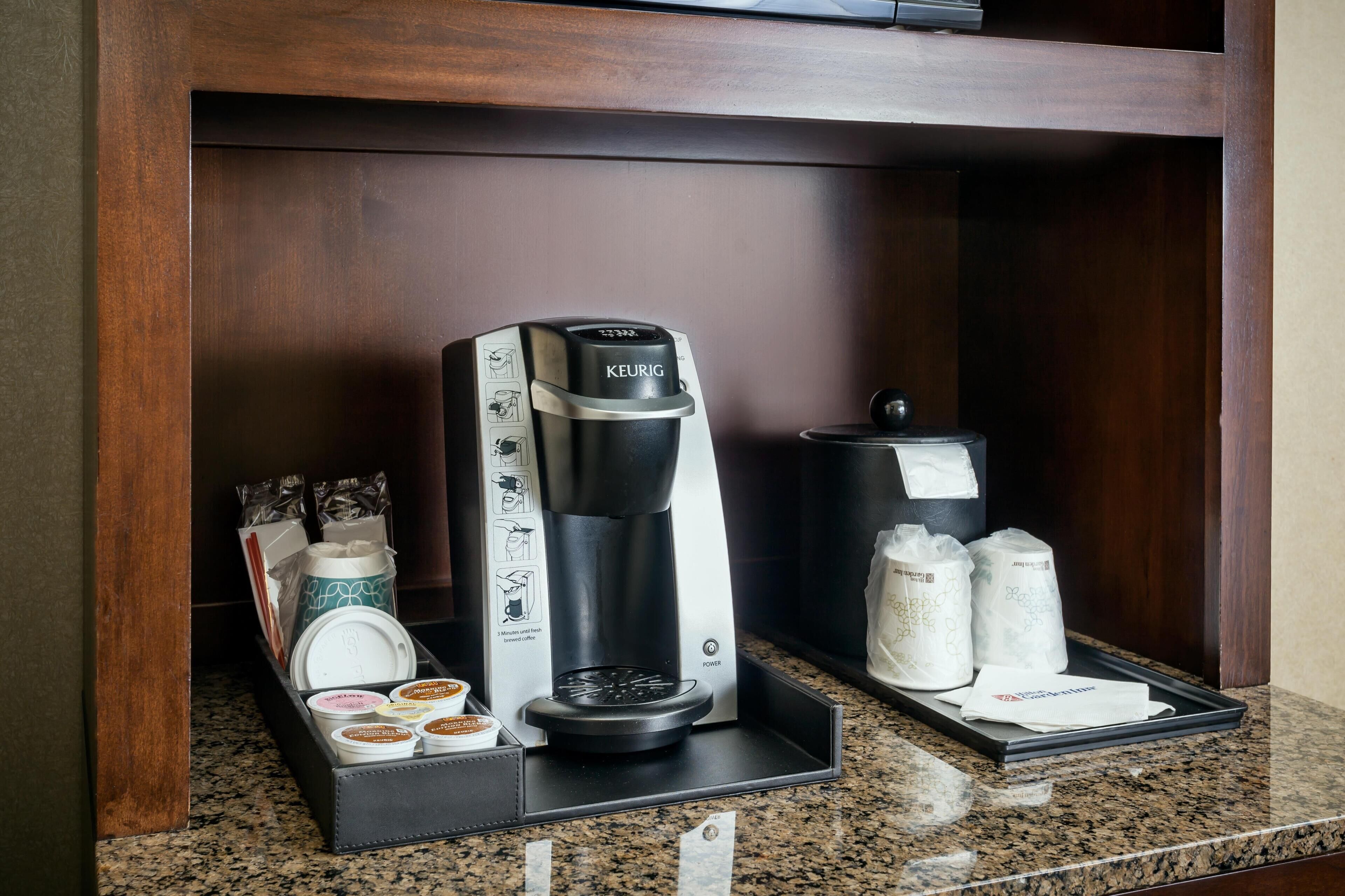 A coffee maker, coffee pods, and sugar packets on a tray in a hotel room.