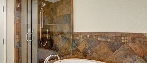 A bathroom with a glass-enclosed shower, a freestanding bathtub, and a tiled wall with a geometric pattern.
