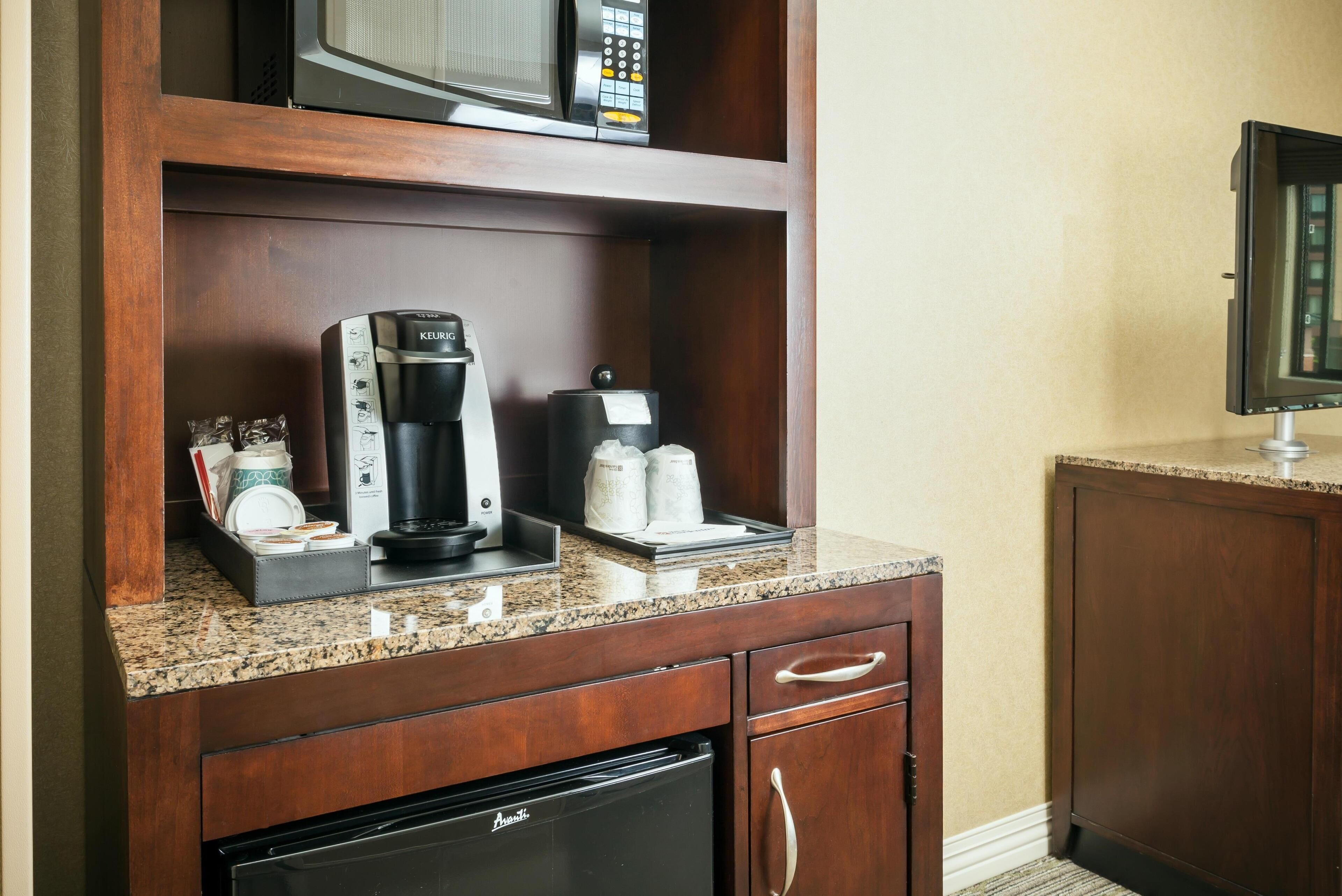 A kitchenette with a coffee maker, microwave, and refrigerator.