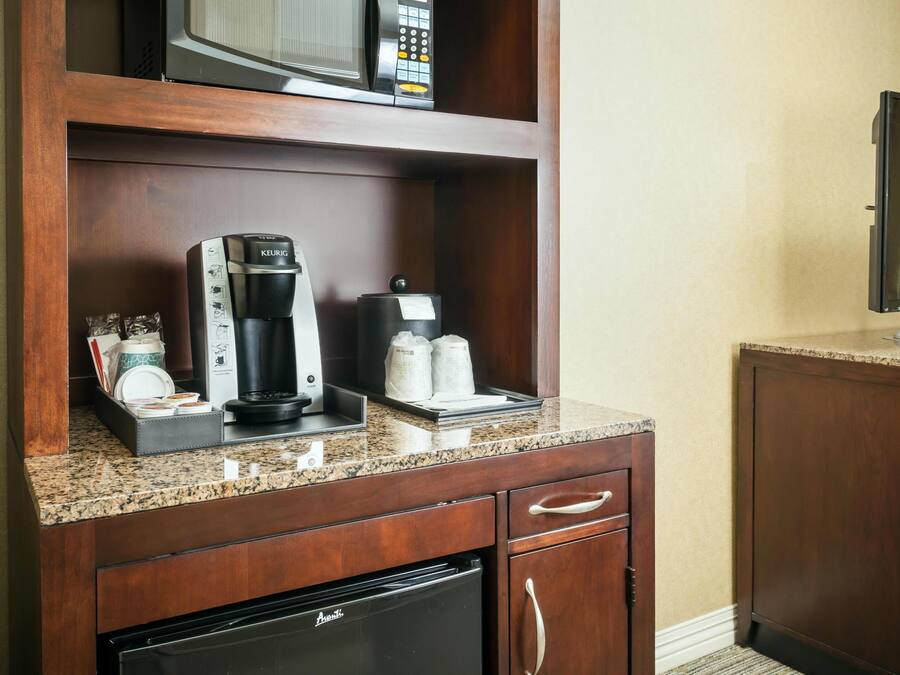 A kitchenette with a coffee maker, microwave, and refrigerator.