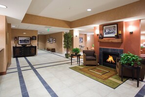 A hotel lobby with a reception desk, seating area, fireplace, and a large plant. - Holiday Inn Express Rawlins by IHG (Rawlins)