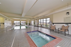 An indoor swimming pool with a tiled floor, a pool ladder, and a seating area with chairs. - Holiday Inn Express Rawlins by IHG (Rawlins)