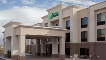A Holiday Inn Express building with a clear entrance, outdoor seating area, and a sign indicating a 14'0' clearance.
