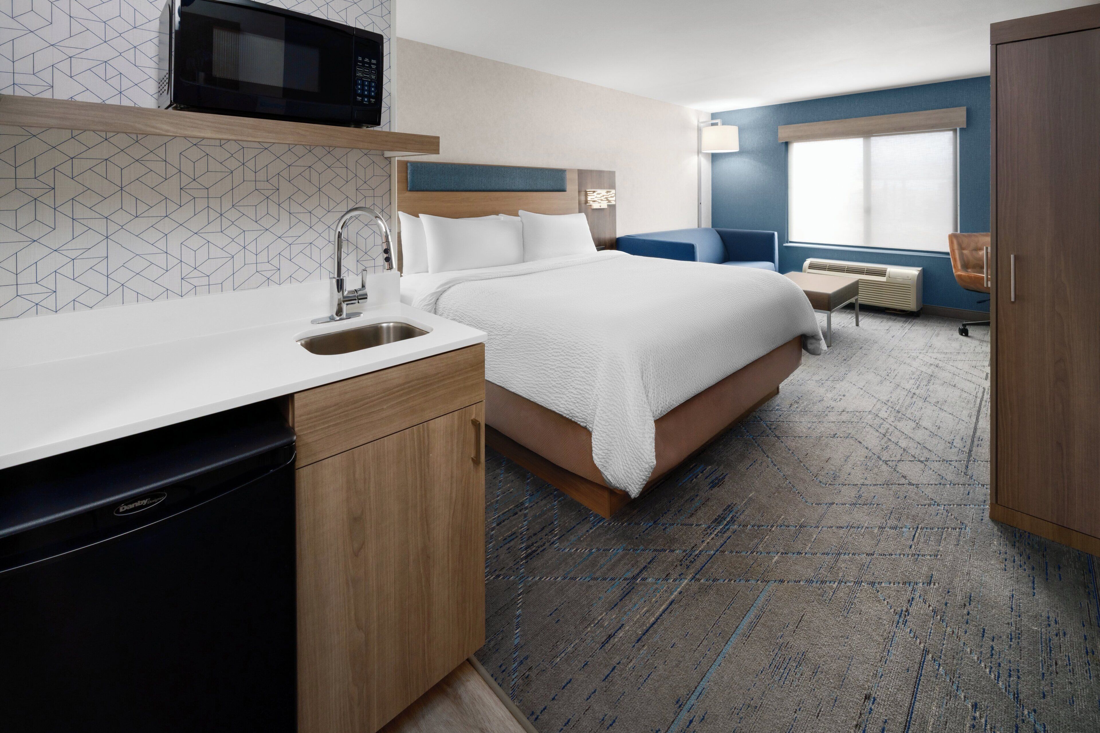 Une chambre d’hôtel avec un lit, un lavabo, un four à micro-ondes et une fenêtre.