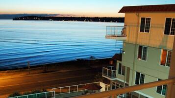 A pool area with lounge chairs and umbrellas, overlooking a body of water.