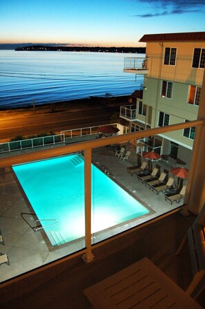 A pool area with lounge chairs and umbrellas, overlooking a body of water.