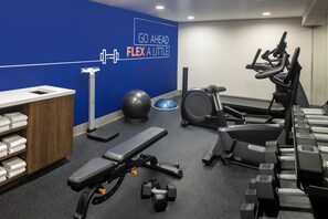 A gym with exercise equipment, a wall with motivational text, and a towel rack. - Holiday Inn Express NYC Chelsea – NoMad Area by IHG (New York)