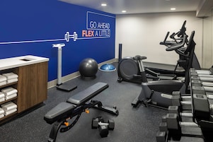A gym with exercise equipment, a wall with motivational text, and a towel rack.