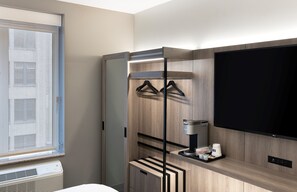 A modern hotel room with a large TV, a coffee machine, and a wardrobe with a mirror. - Holiday Inn Express NYC Chelsea – NoMad Area by IHG (New York)