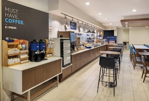 A modern cafe with a coffee station, yogurt and egg dispensers, and seating areas.
