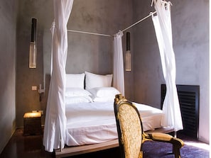 A bedroom with a four-poster bed, a chair, and a bedside table. - Caol Ishka Hotel (Syracuse)