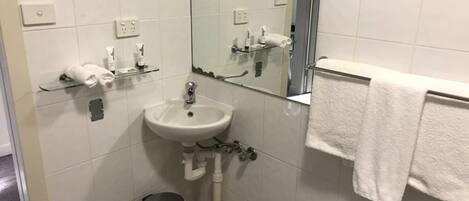 A bathroom with a sink, mirror, towel rack, and trash can.