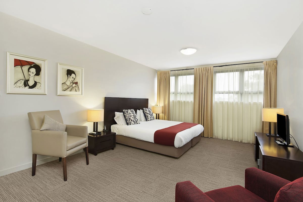 Une chambre d’hôtel avec un lit, une chaise, un bureau et deux lampes.