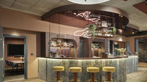 Un espace bar doté d’un comptoir incurvé, de tabourets de bar et d’un écran de télévision.