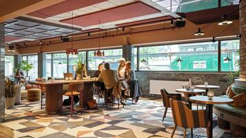 Un café au sol orné de motifs géométriques, avec des meubles en bois et de grandes fenêtres donnant sur la rue.