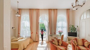 A spacious living room with a large bed, a sofa, and a television. - Spa Hotel Europa Royale Druskininkai (Druskininkai)
