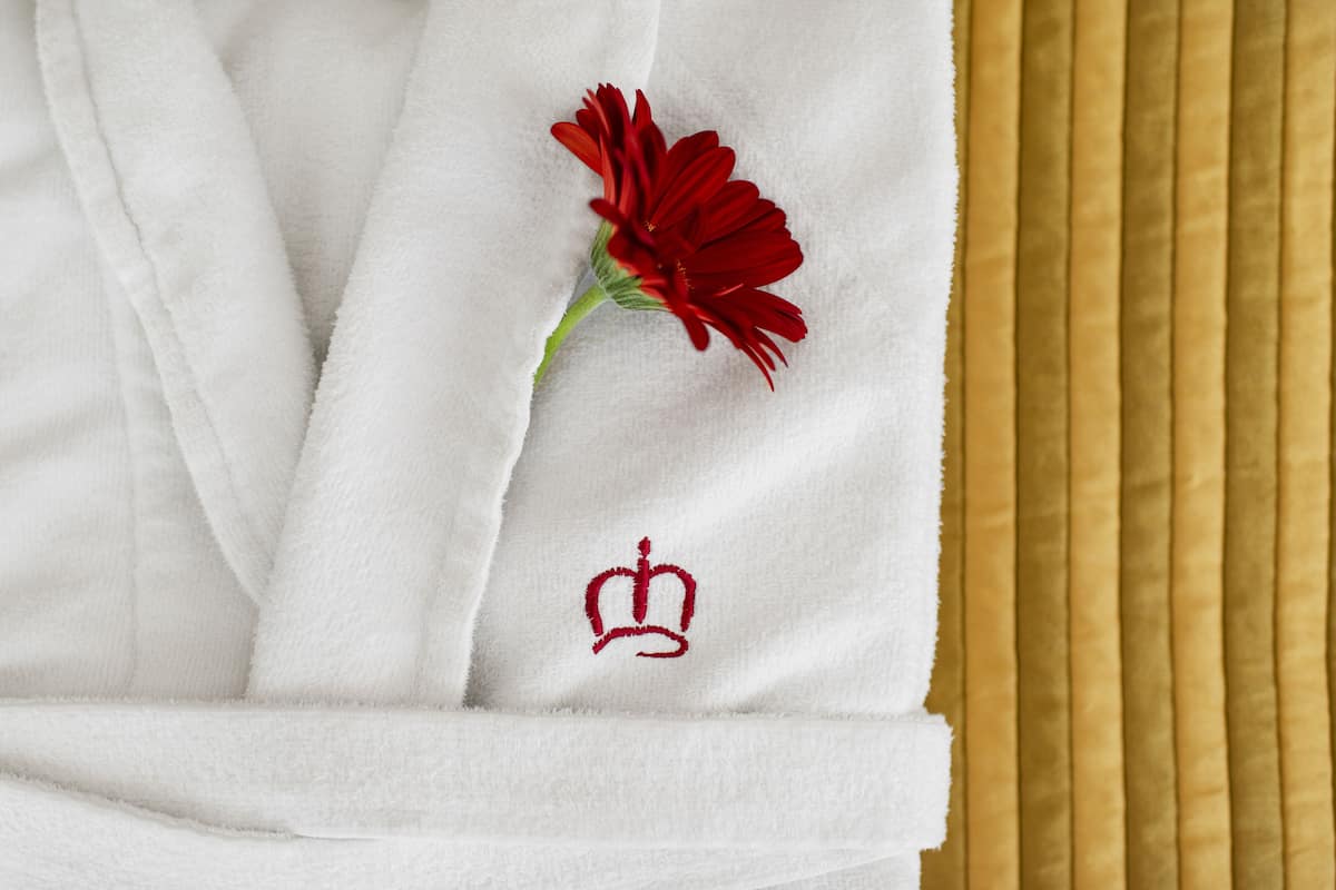 Une robe blanche ornée d’une fleur rouge et d’un emblème représentant une couronne.