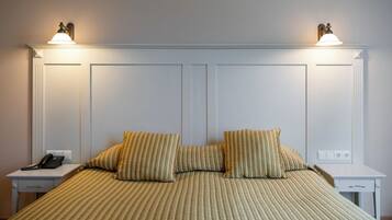 Quarto de hotel com uma cama, duas mesas de cabeceira, telefone e luminárias fixadas na parede.