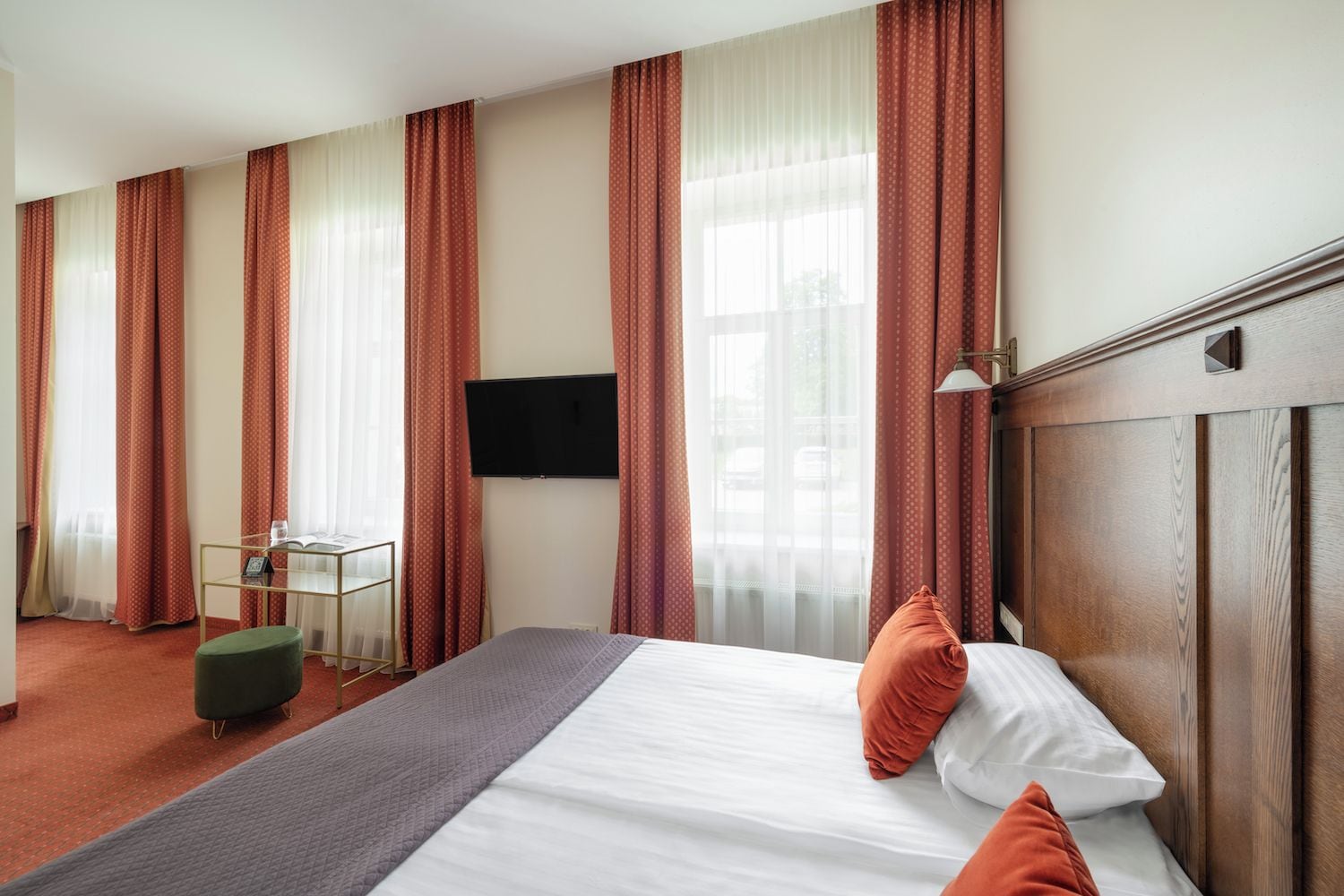 A hotel room with a bed, a desk, a chair, and a TV.