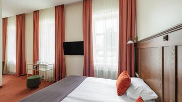 A hotel room with a bed, a desk, a chair, and a TV.