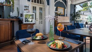 A dining area with a table set for two, featuring a plate of food and a glass of red wine. - Spa Hotel Europa Royale Druskininkai (Druskininkai)