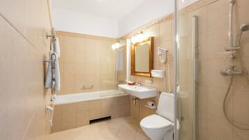 A modern bathroom with a bathtub, sink, toilet, and glass shower enclosure.
