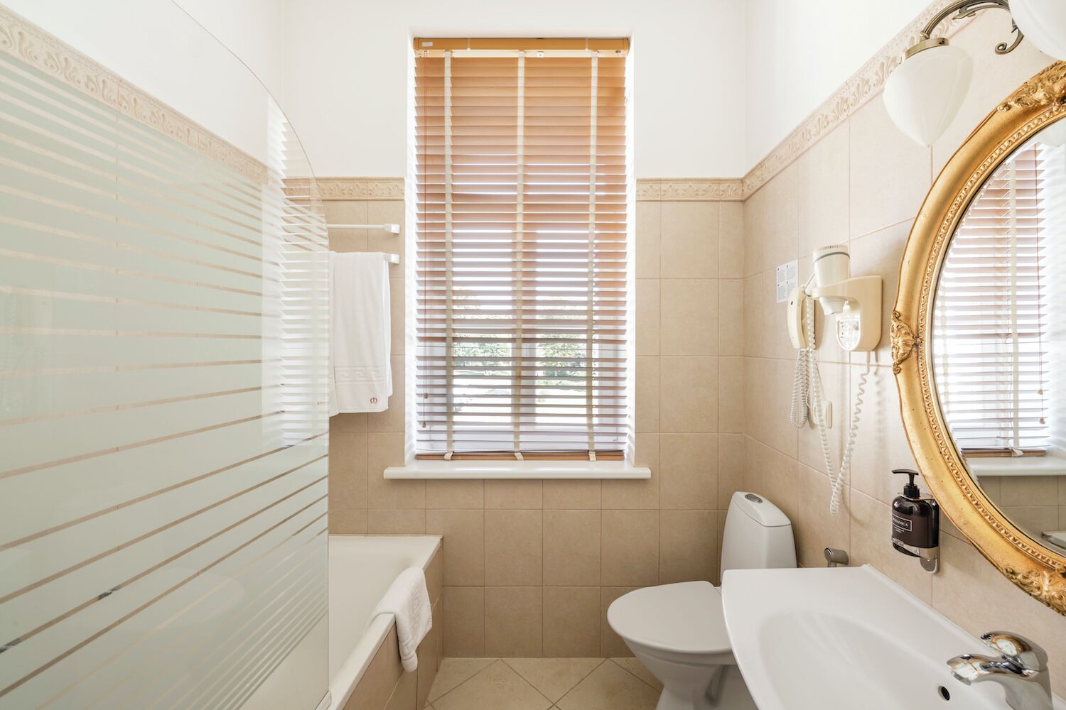 A bathroom with a toilet, sink, and window with blinds.