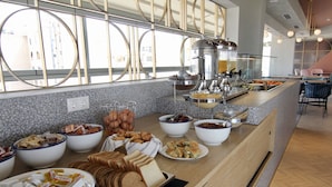 A buffet with various food items and a modern interior design. - Evripides Hotel (Athens)