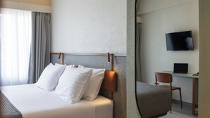 A hotel room with a bed, a desk with a laptop, a television, and a chair. - Evripides Hotel (Athens)
