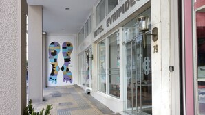 A hotel entrance with a modern design, featuring a glass facade and a colorful mural on the wall. - Evripides Hotel (Athens)