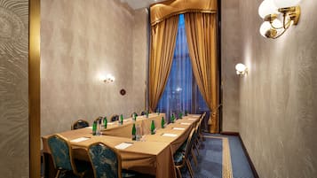 Un salón de conferencias con una larga mesa, sillas y una alfombra azul estampada.