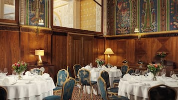Un comedor formal con varias mesas dispuestas para el servicio, paneles de madera y azulejos decorativos.