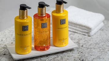 Tres botellas de loción para manos y cuerpo sobre una bandeja blanca.