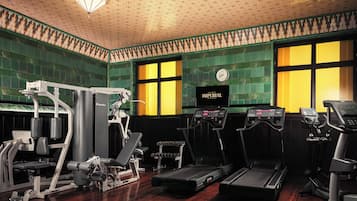 Un gimnasio con cintas de correr, máquinas de pesas y un reloj de pared.