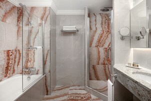 Un bagno moderno con doccia vetrata, pavimento in marmo e mobile lavabo con lavandino e specchio.