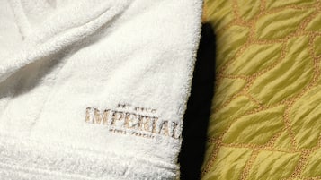 Toalha branca com texto bordado e um travesseiro acolchoado verde.