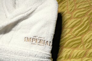 Ein weißes Handtuch mit eingesticktem Text und ein grün gestepptes Kopfkissen.