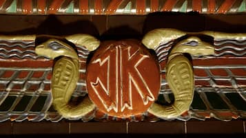 A decorative wall with a central emblem featuring a stylized 'K' and two mythical creatures.