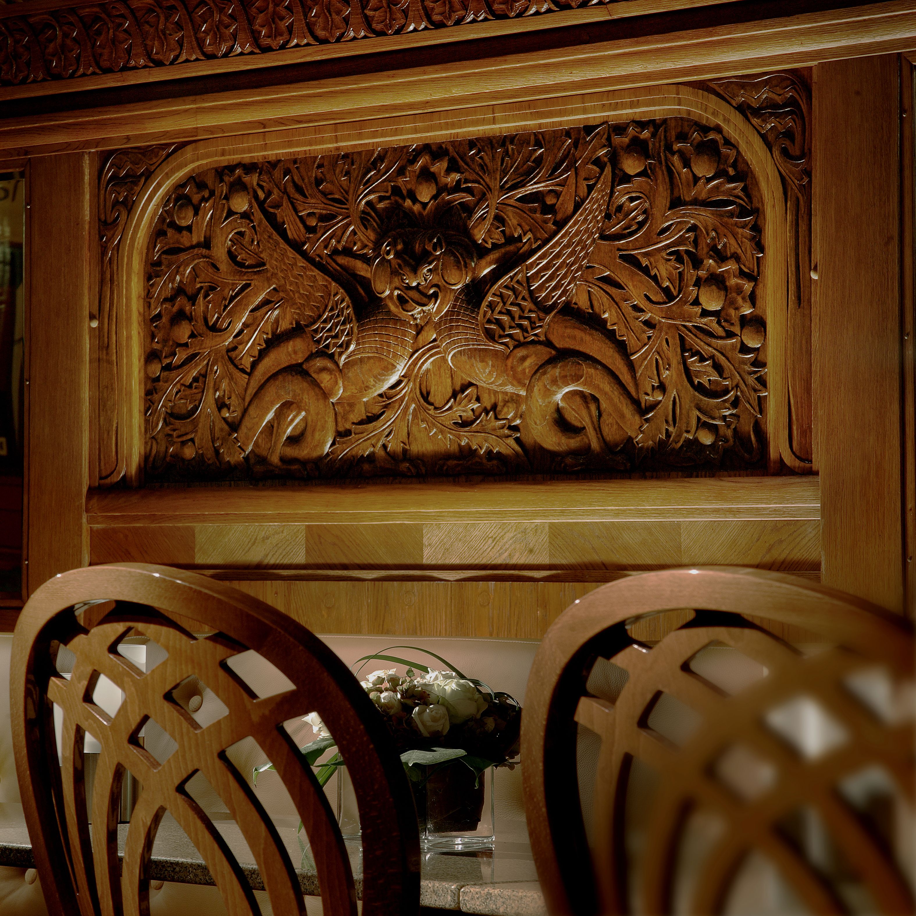 A wooden carved panel above a table with chairs.