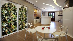 A modern interior with a round dining table, white chairs, and a decorative wall with a floral pattern. - FAVIGNANA HOTEL Concept Holiday (Favignana)