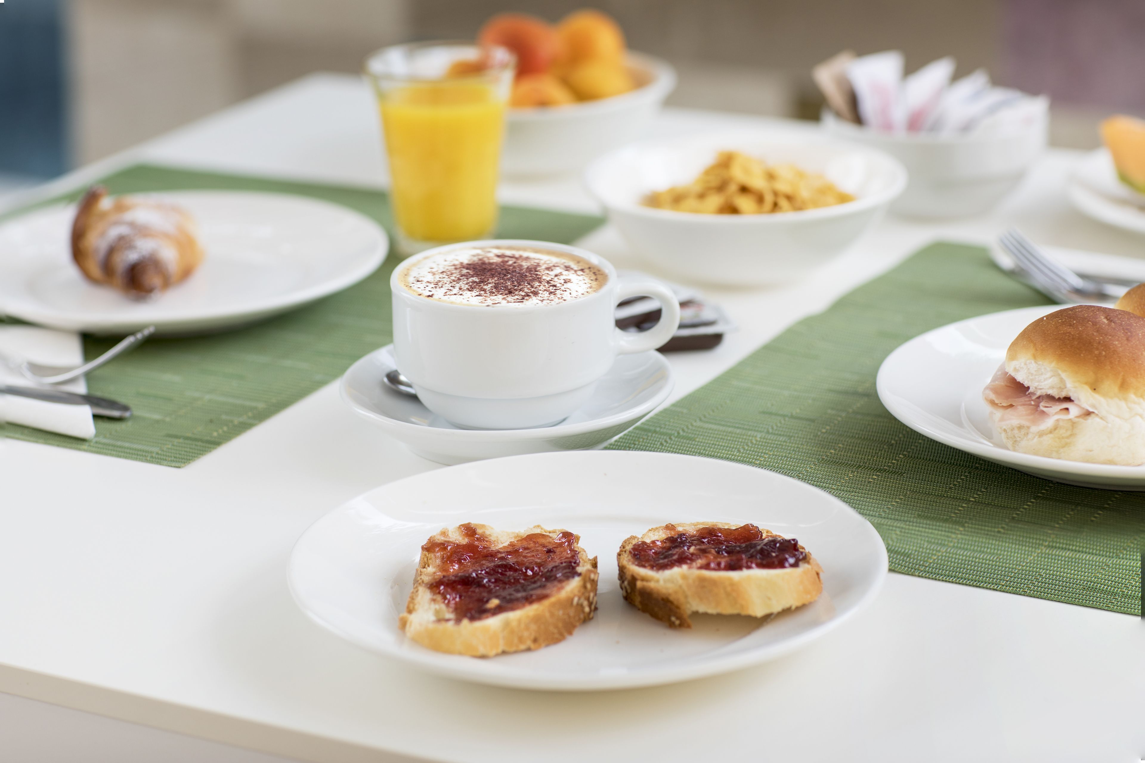 A breakfast table with various food items including toast, a cup of coffee, and a bowl of fruit.