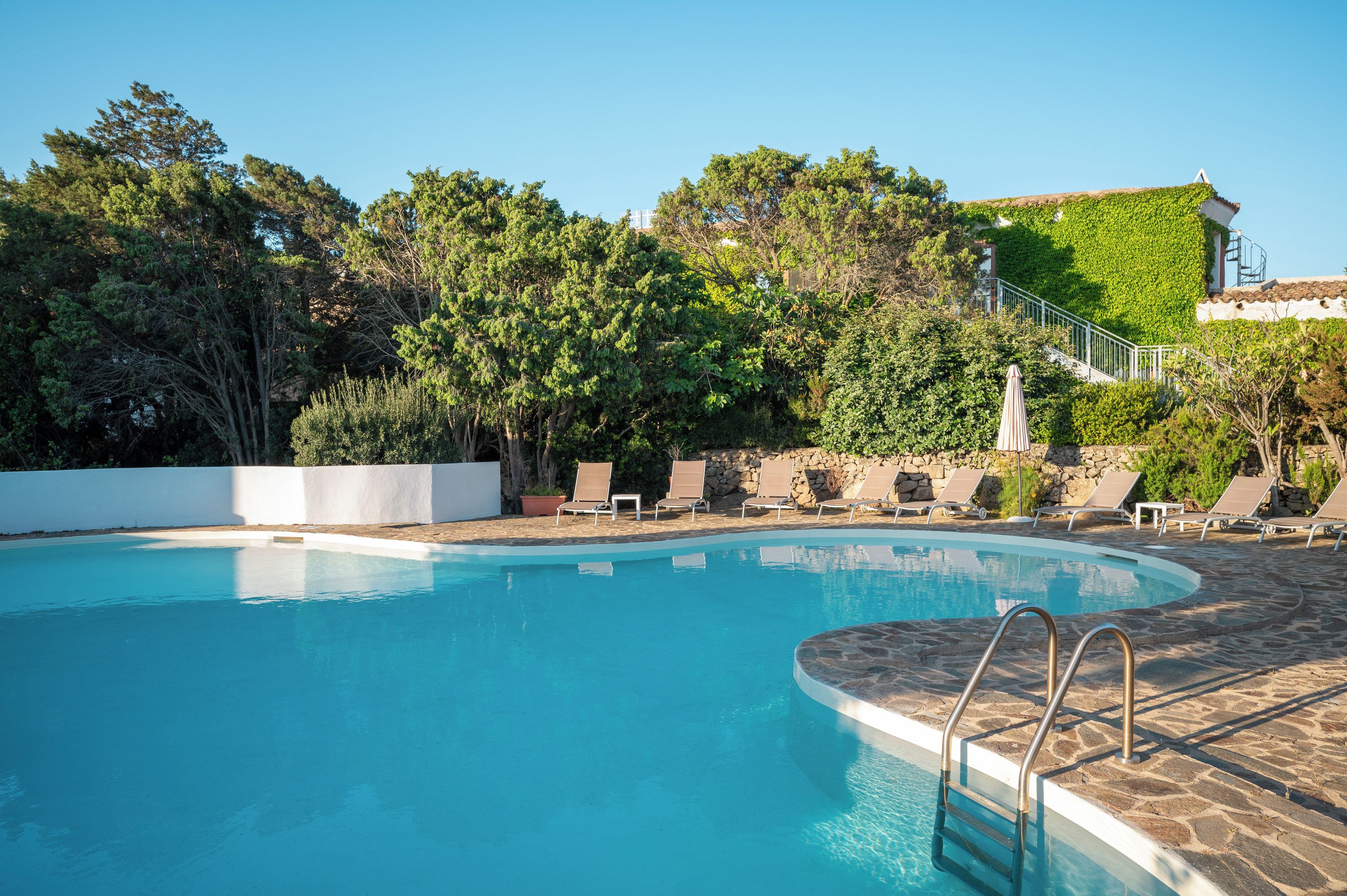 Una piscina al aire libre, sombrillas, sillones reclinables de piscina