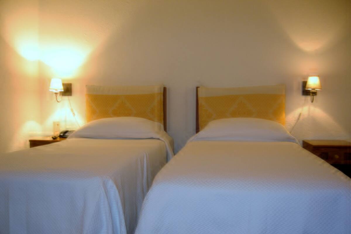 Two single beds with headboards and nightstands, each with a lamp.