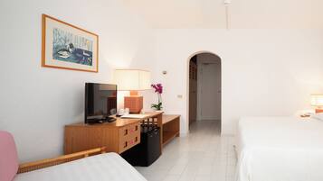 Una habitación de hotel con una cama, un escritorio con computadora, televisión y lámpara.