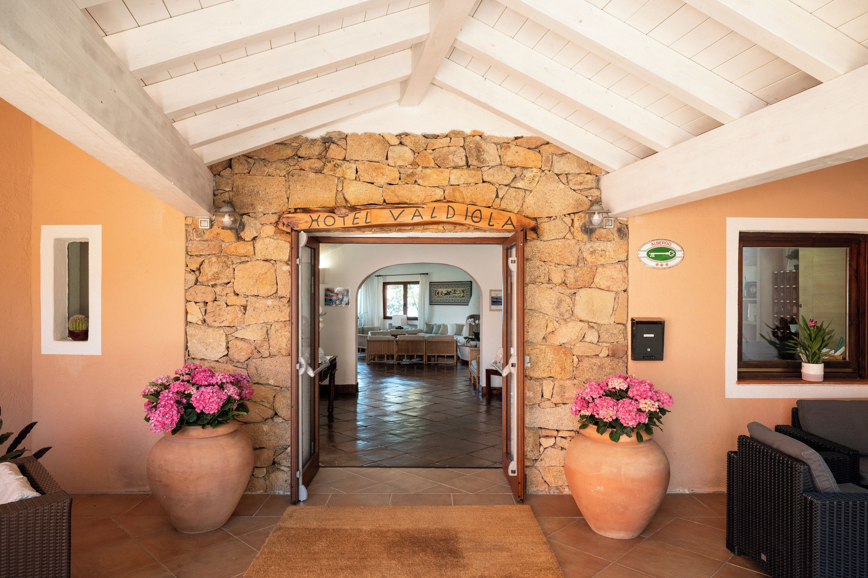 A hotel entrance with a stone archway, a reception desk, and a view into the lobby.