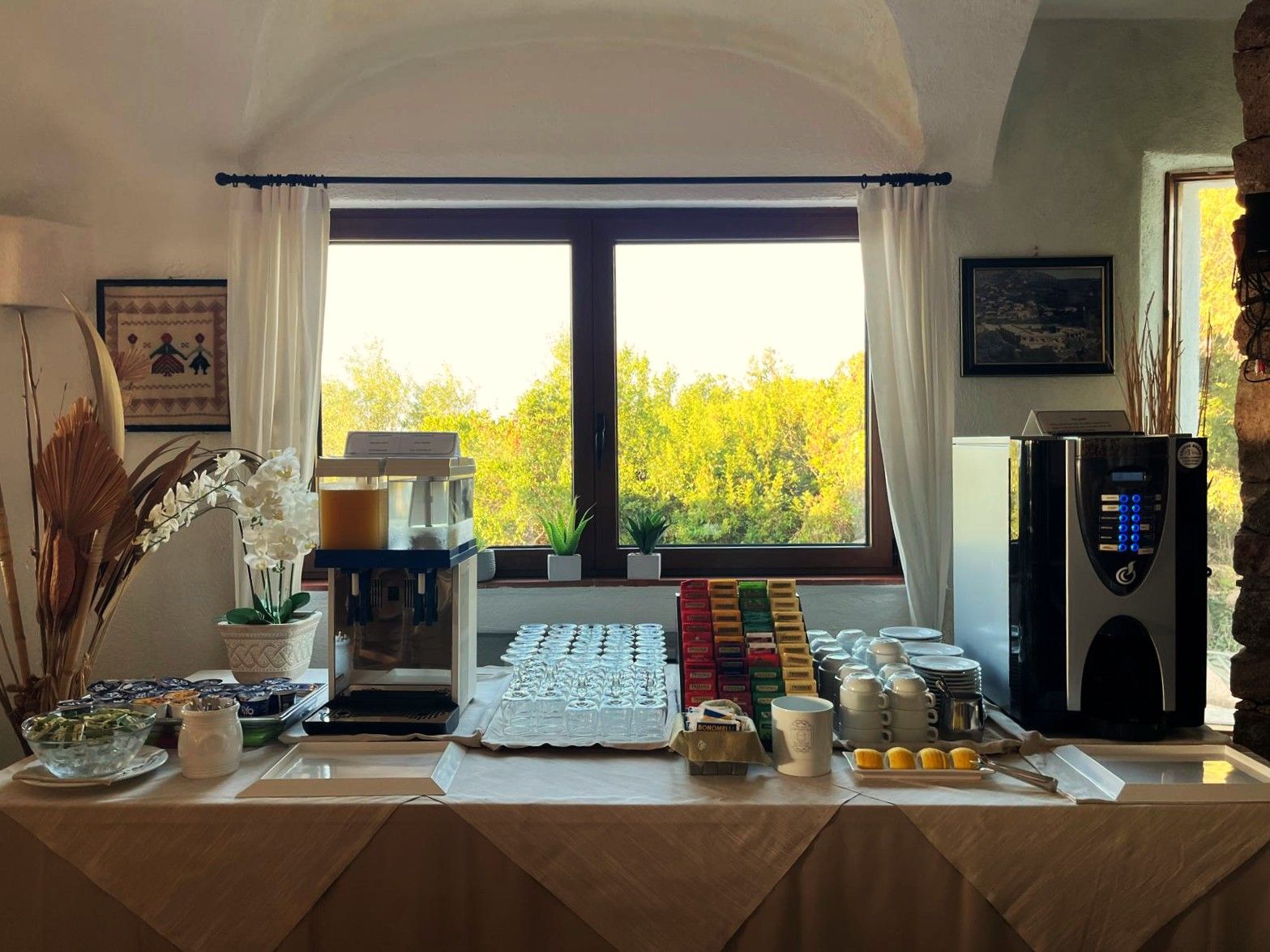 Un'area colazione a buffet con macchina del caffè, angolo tè e diversi cibi.
